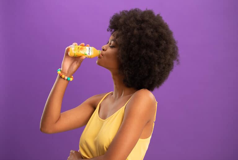 mulher tomando suco da natural one representando a reeducação alimentar
