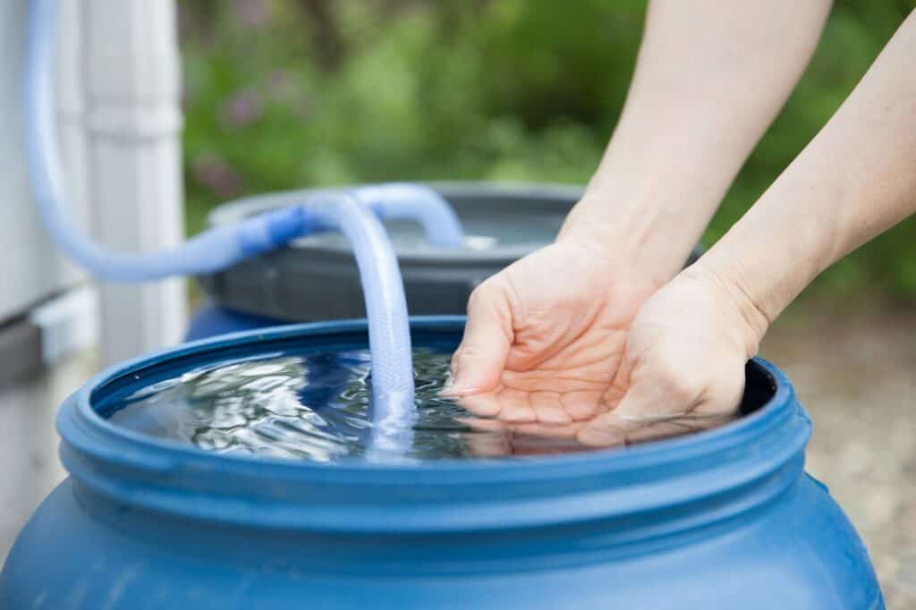 Texto alternativo: Na imagem há uma caixa de água, uma mão dentro do balde