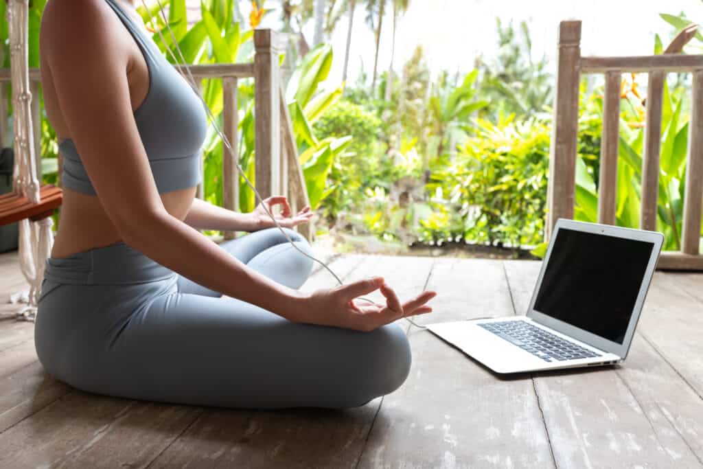 Na imagem há uma mulher em posição de yoga e meditação.