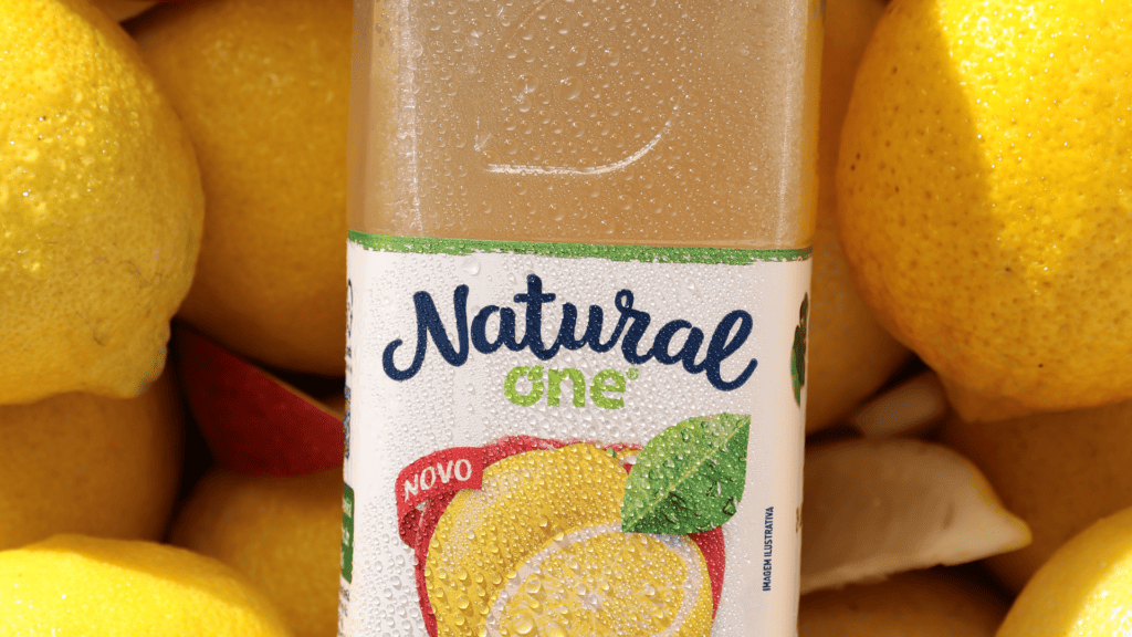 Na imagem há diversos limões sicilianos e sob eles a garrafa de limão siciliano da Natural one