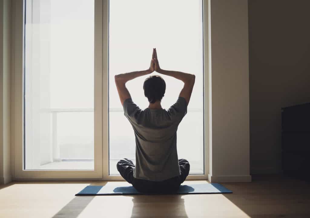 Na imagem há um homem em posição de yoga