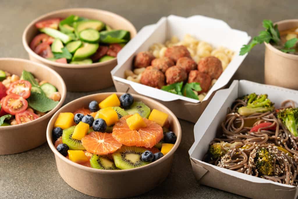 Texto alternativo: na imagem há diversos potes com alimentos. Saladas, massas, arroz e feijão