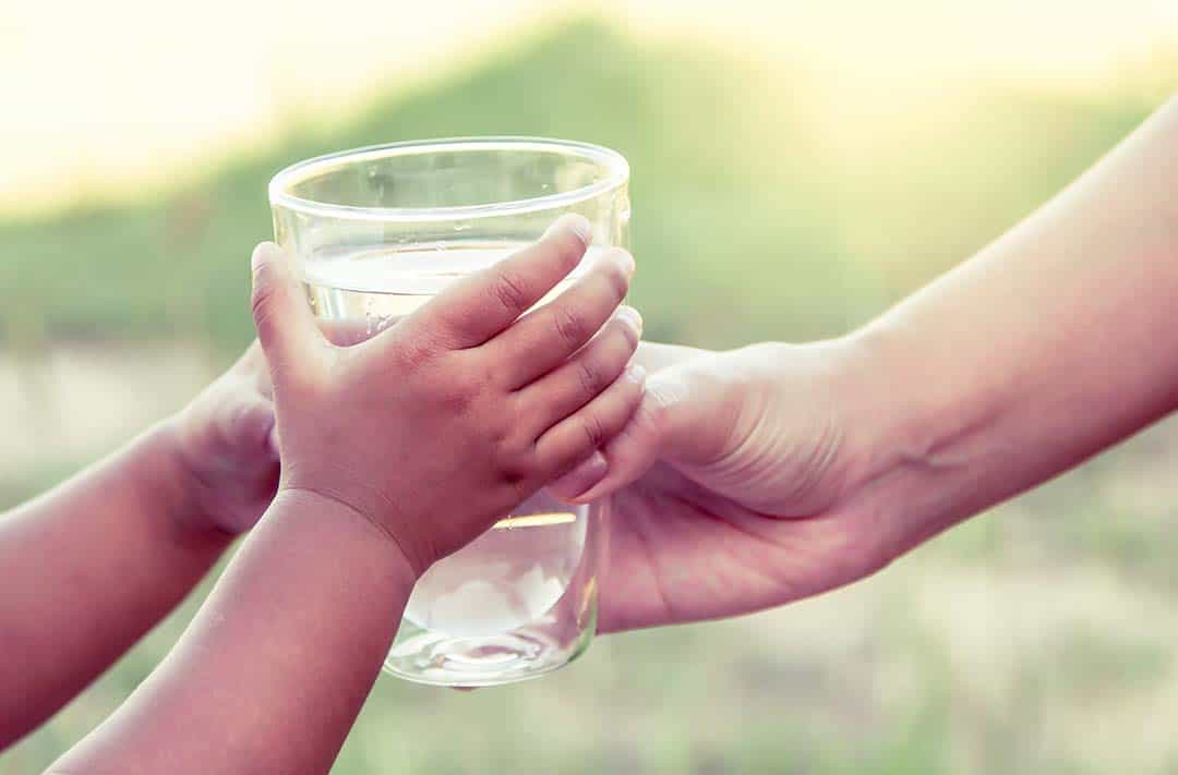 texto alternativo: na imagem há uma mão infantil segurando um copo de água