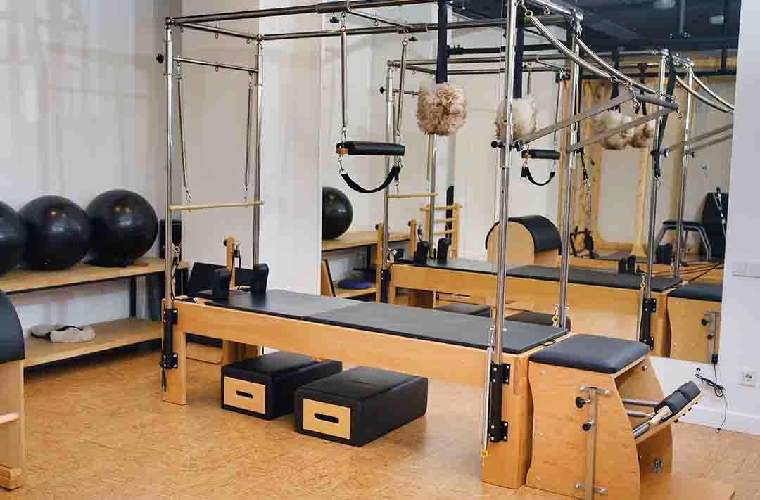 Texto alternativo: uma sala de pilates, com diversos equipamentos e instrumentos para a aula, como bolas, cordas e steps.