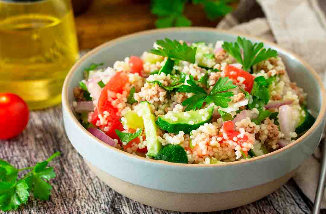 Texto alternativo: na imagem vemos uma colorida salada de quinoa com legumes dentro de um bowl e sob uma toalha de mesa.